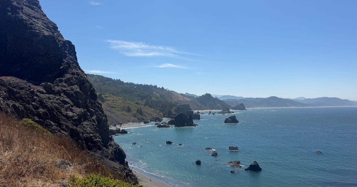 Beautiful view of the Oregon coastline with rocky cliffs and clear blue ocean under a sunny sky.